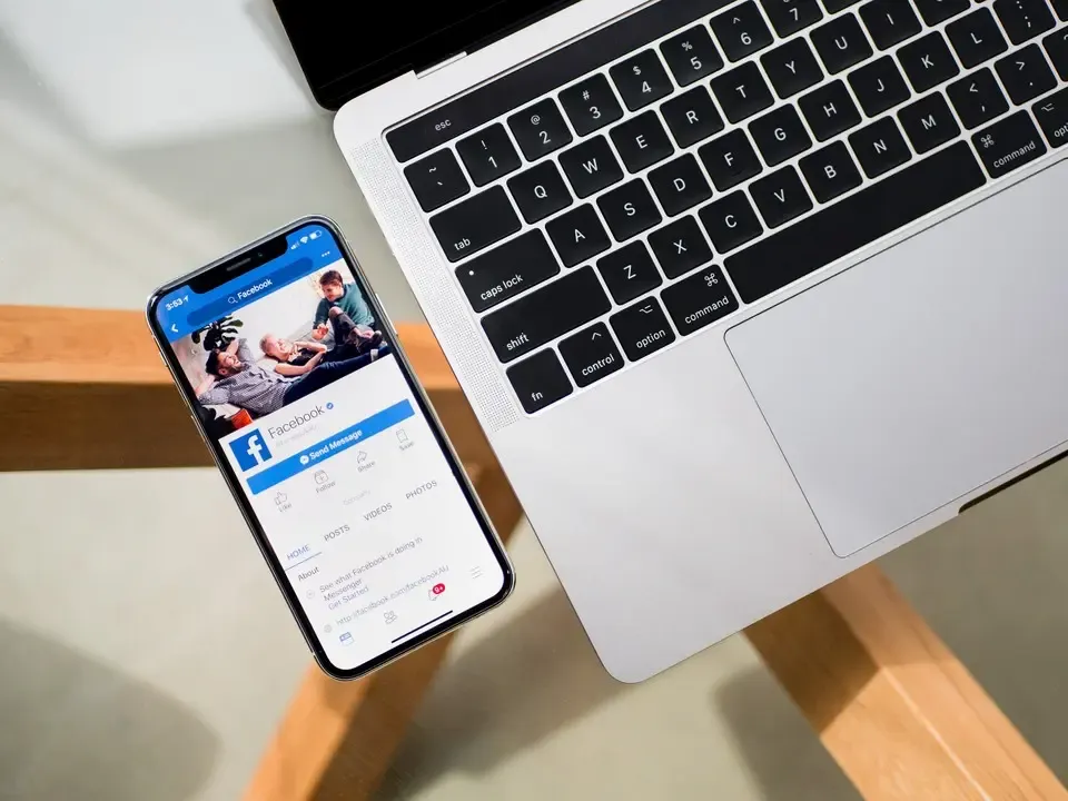 Facebookpagina op een telefoon naast een laptop